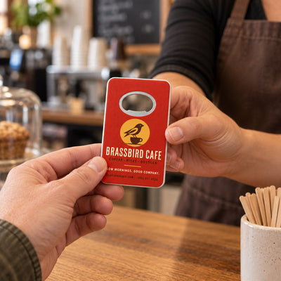 Cafe Logo custom logo bottle opener magnet - handed to a customer