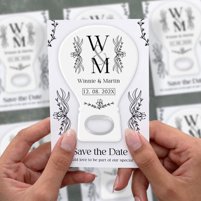 Minimal Botanical Monogram save the date bottle opener magnet shown in hand on its printed background card