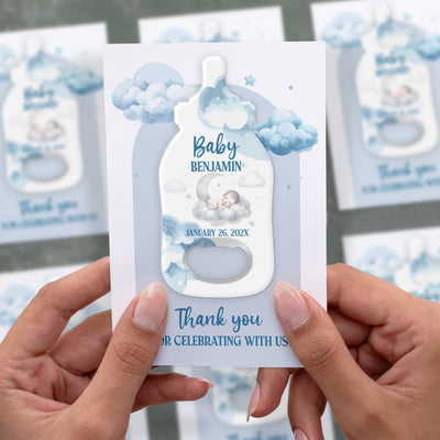 Sleeping Baby Clouds baby shower bottle opener magnet shown in hand on its printed background card