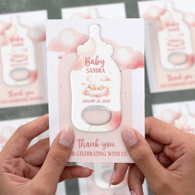 Pink Clouds baby shower bottle opener magnet shown in hand on its printed background card