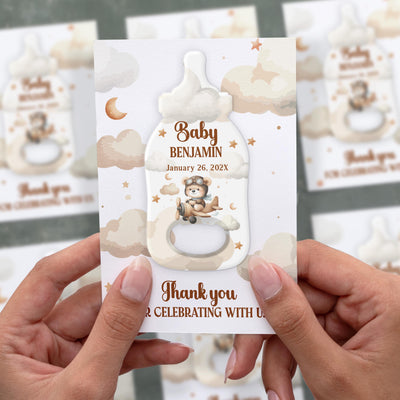 Welcome baby shower bottle opener magnet shown in hand on its printed background card