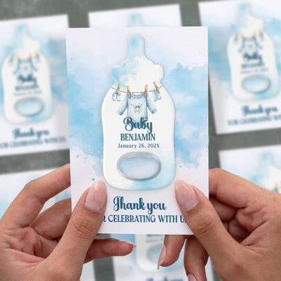 Watercolor Baby Clothes baby shower bottle opener magnet shown in hand on its printed background card