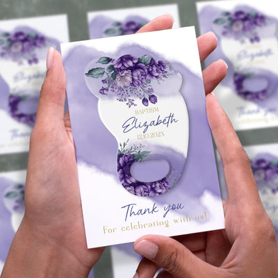 Purple Floral Footprint baptism bottle opener magnet shown in hand on its printed background card