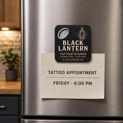 Tattoo Studio custom logo bottle opener magnet - held on a refrigerator door by its magnetic back